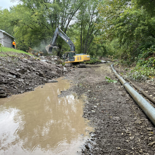 Walton Village's West Brook stream well bank stabilization project remediation showing large excavator reconfiguring streambank soil.